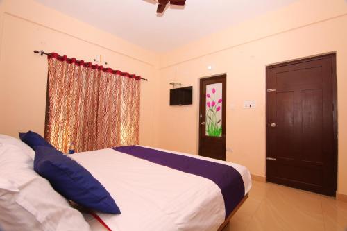 a bedroom with a bed with blue pillows and a window at Pine Tree Munnar in Munnar