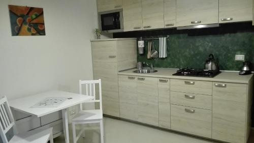 cocina con armarios blancos, mesa y fregadero en Casa Millegrü, en Pisa