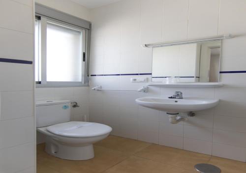 a white bathroom with a toilet and a sink at Albergue Inturjoven Malaga in Málaga