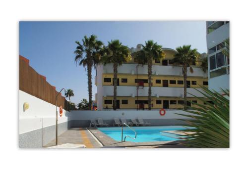 budynek z basenem i palmami w obiekcie Apartamentos Calma w mieście Playa del Ingles