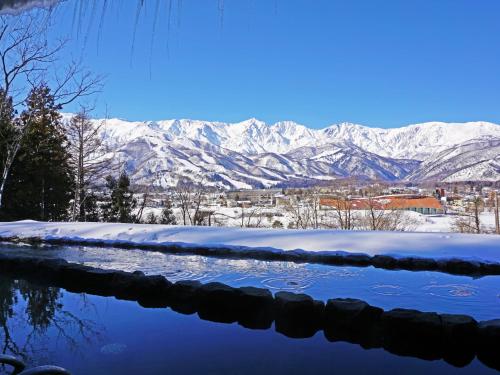 a pool of water with snowy mountains in the background at Hakuba Highland Hotel in Hakuba
