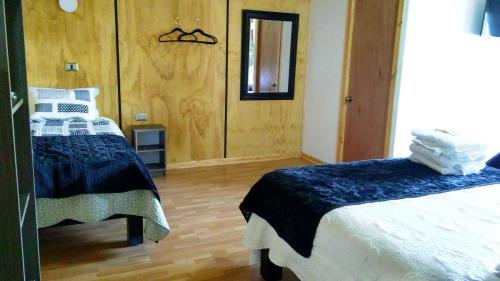 a bedroom with two beds and a mirror at Residencial del Maule in Linares
