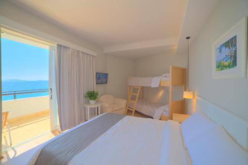 a bedroom with a bed and a window with a balcony at Elea Beach Hotel in Dassia