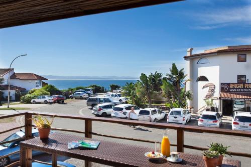 a balcony with a table and cars parked in a parking lot at Aloe Again in Jeffreys Bay