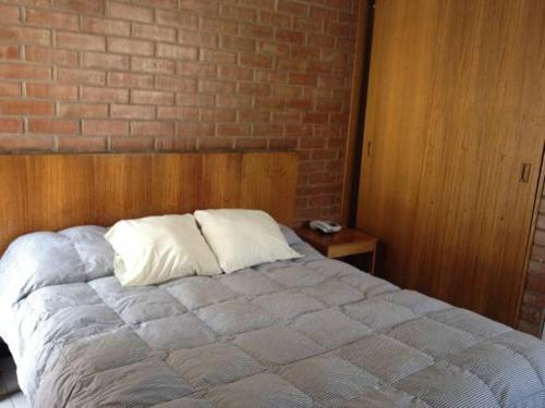 a bed in a bedroom with a brick wall at Aparthotel San Francisco in Santiago