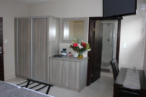 a bathroom with a counter with a vase of flowers at Prost Hotel Swakopmund Namibia in Swakopmund