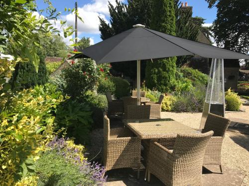 
a patio area with chairs, tables and umbrellas at The Red Lion Inn in Long Compton

