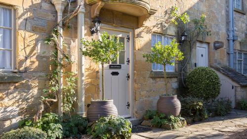 a house with two large vases in front of a door at Box Cottage in Broadway
