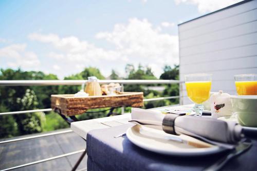 a table with a plate of food and two glasses of orange juice at B&B Villa des Roses in Hasselt