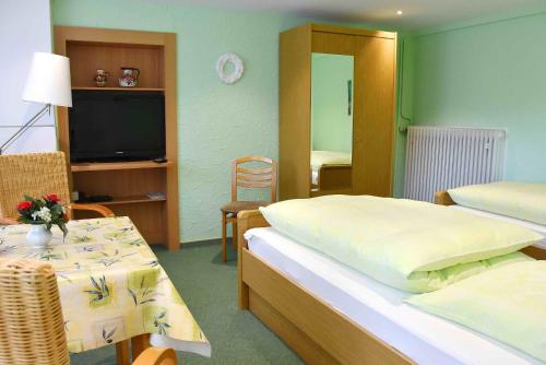 1 dormitorio con cama, mesa y TV en Ferienwohnungen Hildegund, en Uschlag