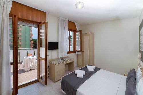 sypialnia z łóżkiem i biurkiem oraz balkon w obiekcie Hotel Airone w Bibione