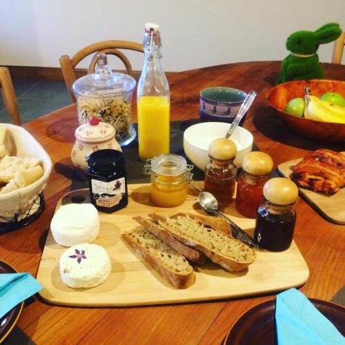 ein Holztisch mit einem Schneidebrett, auf dem Brot und andere Zutaten liegen in der Unterkunft Chantemerle 1741, chambres d'hôtes à la montagne in Sallanches