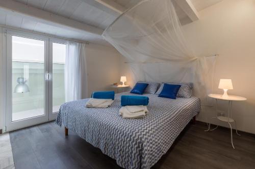ein Schlafzimmer mit einem Bett mit blauen Kissen und einem Fenster in der Unterkunft Villa Unica Terrazzo Sul Mare in Donnalucata