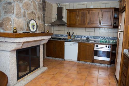 a kitchen with wooden cabinets and a stone fireplace at Casa Da Eira Longa in Vilar