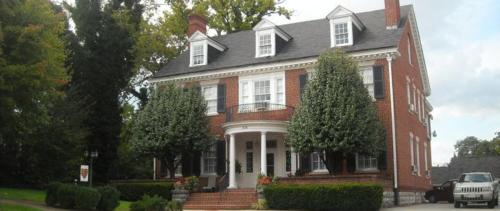 een groot rood bakstenen huis met een witte veranda bij King George Inn in Roanoke