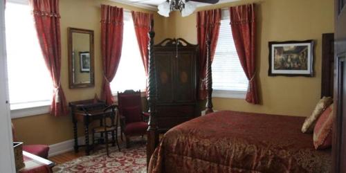 a bedroom with a bed and a chair and windows at King George Inn in Roanoke