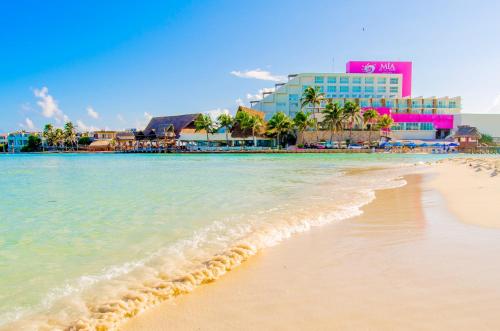 a beach with the ocean and buildings in the background at Mia Reef Isla Mujeres Cancun All Inclusive Resort in Isla Mujeres