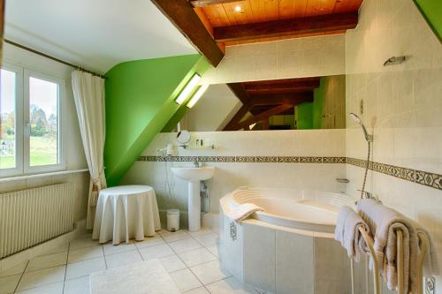 a bathroom with a tub and a green ceiling at Hotel Restaurant des Vosges in Birkenwald