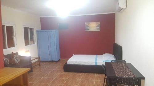 a bedroom with a bed and a red wall at VIP House-Praia Francesca in São Tomé