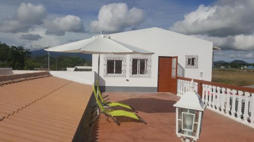 a white house with an umbrella and a patio at VIP House-Praia Francesca in São Tomé