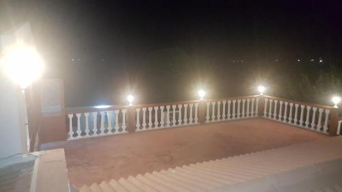 a balcony with lights and a white railing at night at VIP House-Praia Francesca in São Tomé
