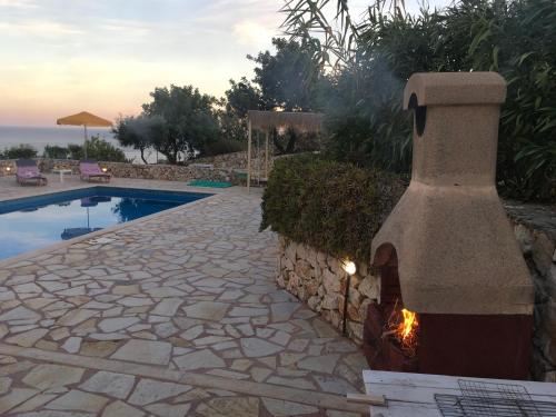 a stone patio with a fireplace next to a pool at Astra Villas in Skala Kefalonias