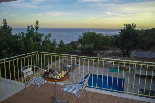a balcony with a table and chairs and a pool at Astra Villas in Skala Kefalonias