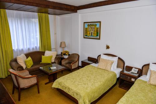 a hotel room with a bed and a couch and chairs at Hotel Grand in Valjevo