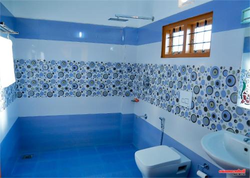 a blue bathroom with a toilet and a sink at Holiday Villa in Thekkady