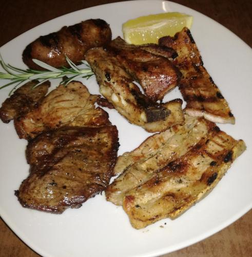 a plate of food with meat and a slice of lemon at Hotel Relais Valle Orientina in Pitigliano