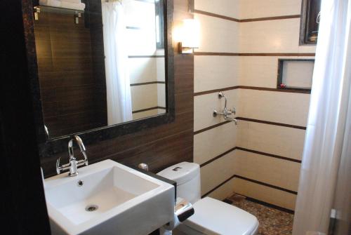 uma casa de banho com um lavatório, um WC e um espelho. em Le Magnifique em Porvorim