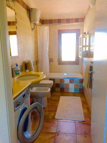 a bathroom with a toilet and a sink and a washing machine at Fattoria di Anja e Marco in Costa Rei