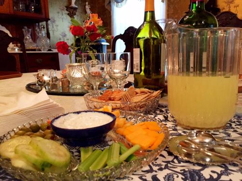 einen Tisch mit Schüsseln zum Essen und einer Flasche Wein in der Unterkunft Holden House 1902 Bed & Breakfast Inn in Colorado Springs