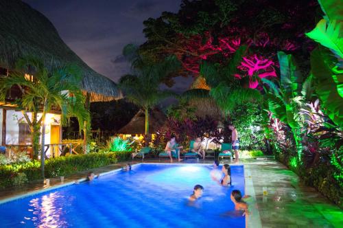un groupe de personnes dans une piscine la nuit dans l'établissement Primaluna Beach Hostel, à Palomino
