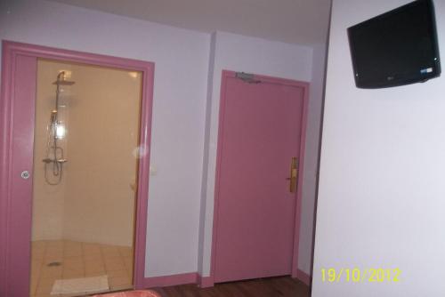 La salle de bains est pourvue d'une porte rose et d'une télévision murale. dans l'établissement Hôtel de la Terrasse, à Paris