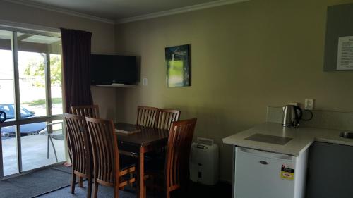 a kitchen with a table and chairs and a kitchen with a refrigerator at High Country Lodge, Motels & Backpackers in Twizel