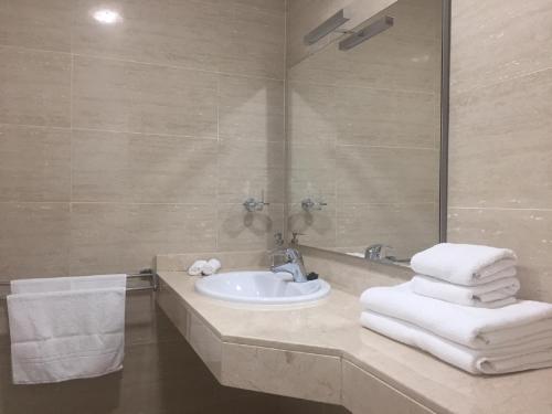 y baño con lavabo, espejo y toallas. en Marina Golf Apartments, en San Miguel de Abona