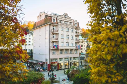 a tall white building in the middle of a street at Art Deco WOLKER by ASTORIA Hotel & Medical Spa in Karlovy Vary