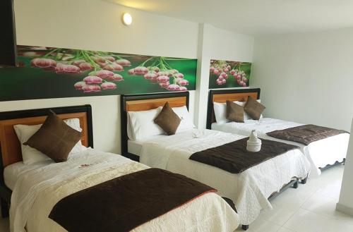 two beds in a room with paintings on the wall at Hotel Santa Monica in Fusagasuga