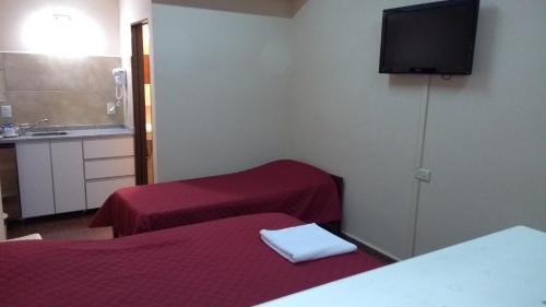 a room with two beds and a flat screen tv at Apart Office in San Miguel de Tucumán