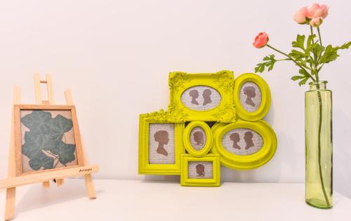 a group of pictures in a yellow frame next to a vase at Parliament & River View Apartments in Bucharest