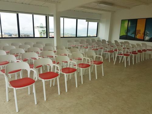 a room filled with white chairs with red seats at Hotel Santa Monica in Fusagasuga