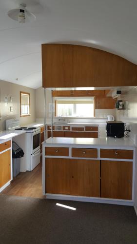 a large kitchen with wooden cabinets and white appliances at High Country Lodge, Motels & Backpackers in Twizel