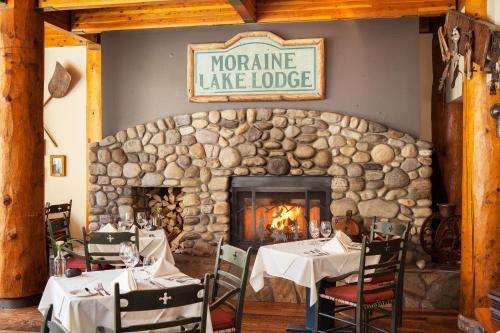 a restaurant with two tables and a stone fireplace at Moraine Lake Lodge in Lake Louise