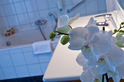 Ein Haufen weißer Blumen auf einer Theke im Badezimmer. in der Unterkunft Cocoon Hotel Belair in Bourscheid