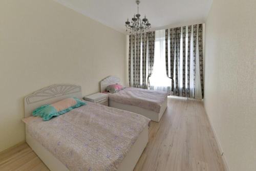 een slaapkamer met 2 bedden en een kroonluchter bij Apartment Lux 177 A, ЭКСПО, Mega Silky Way in Astana