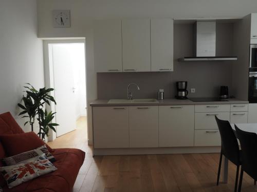 a kitchen with white cabinets and a couch in a room at Appartement place Golbéry in Strasbourg