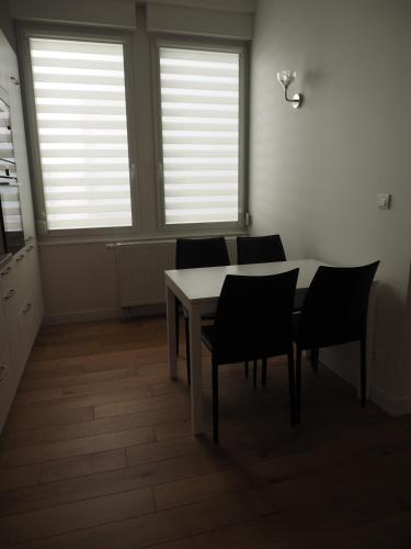 a dining room with a table and chairs and windows at Appartement place Golbéry in Strasbourg
