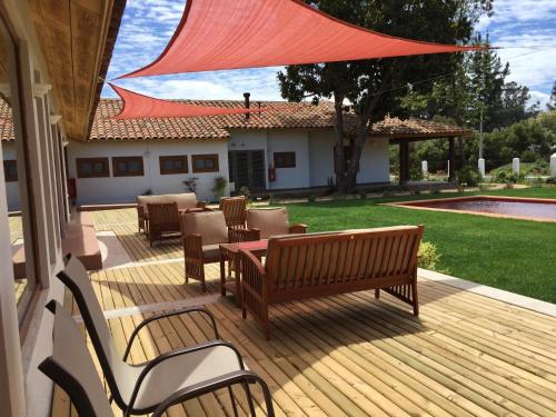 a wooden deck with chairs and a table with a red umbrella at Hotel Boutique BC Wine Casablanca in Casablanca