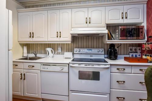 a kitchen with white cabinets and a stove top oven at Noble Waterfront Suites in Brockville